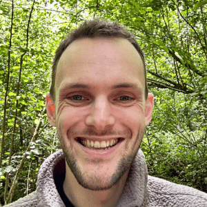 A photo of David smiling, he has short hair and blue eyes