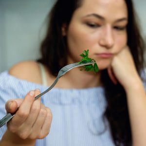 A photo of a woman holding a forkful of herbs