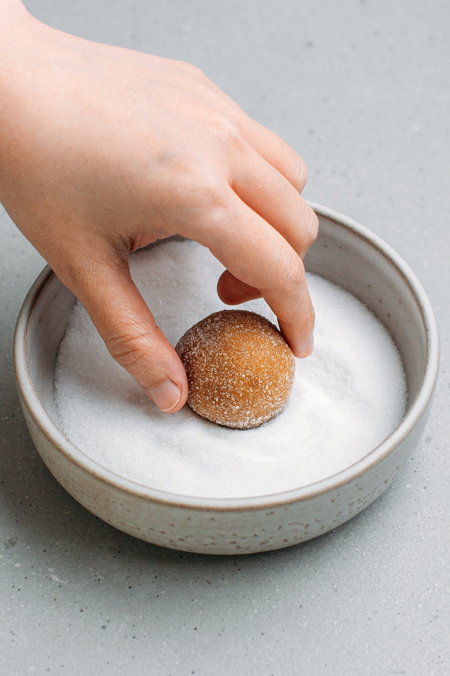 Rolling a ball of cookie dough in granulated sugar.
