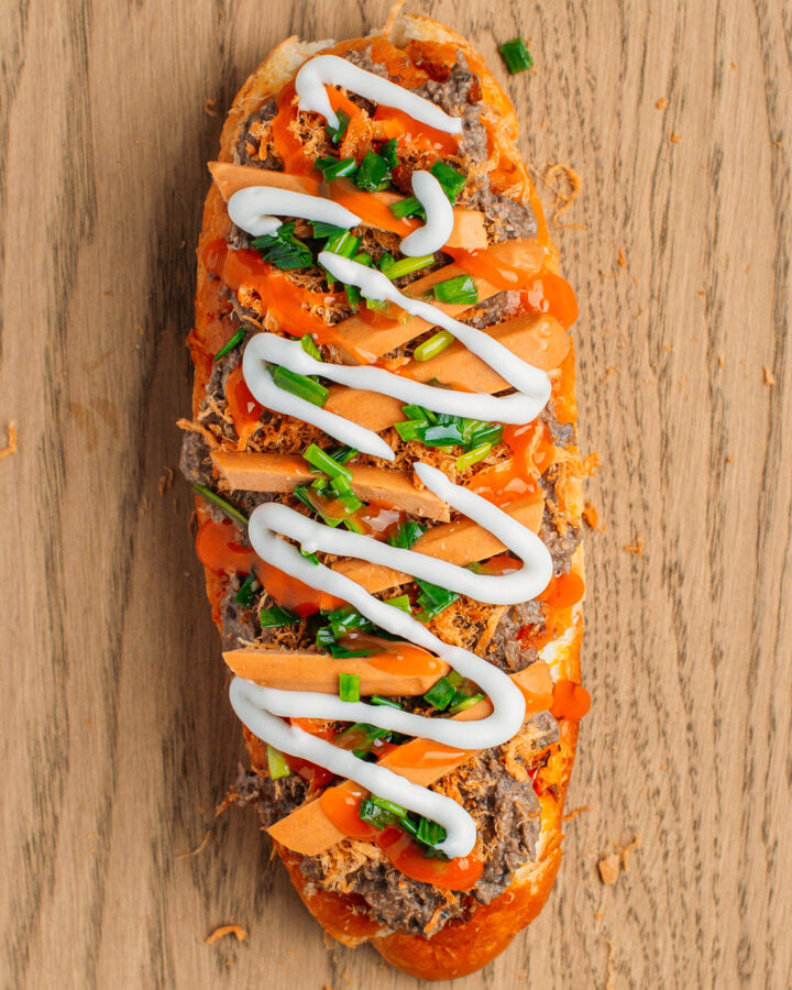 Grilled banh mi bread topped with pâté, sausages, mayo, and sweet chili sauce.