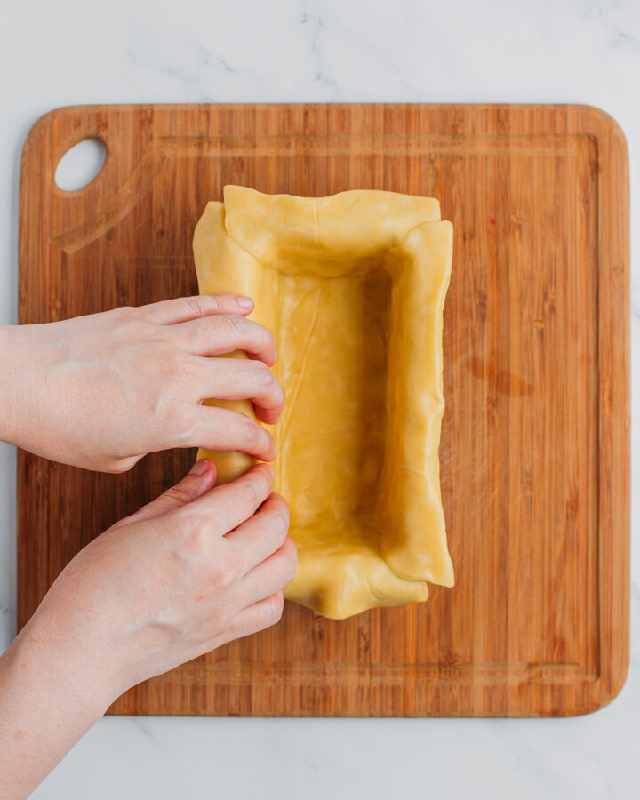 Pressing a pie crust into a rectangle baking pan.