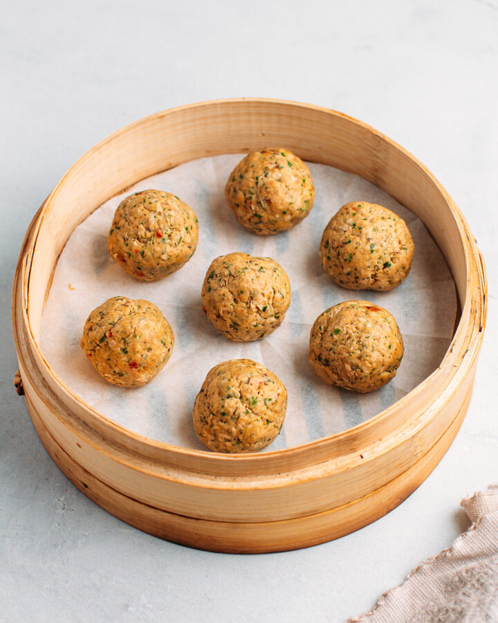 Uncooked vegan meatballs in a bamboo basket steamer.