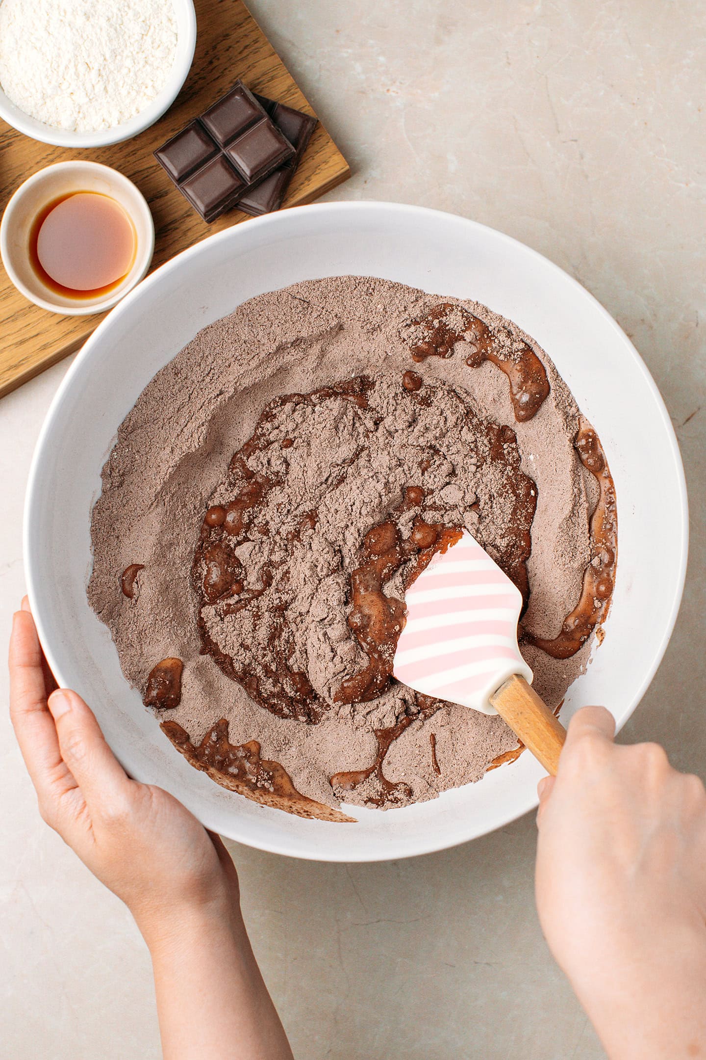 Mixing flour, cocoa powder, and melted chocolate in a mixing bowl.