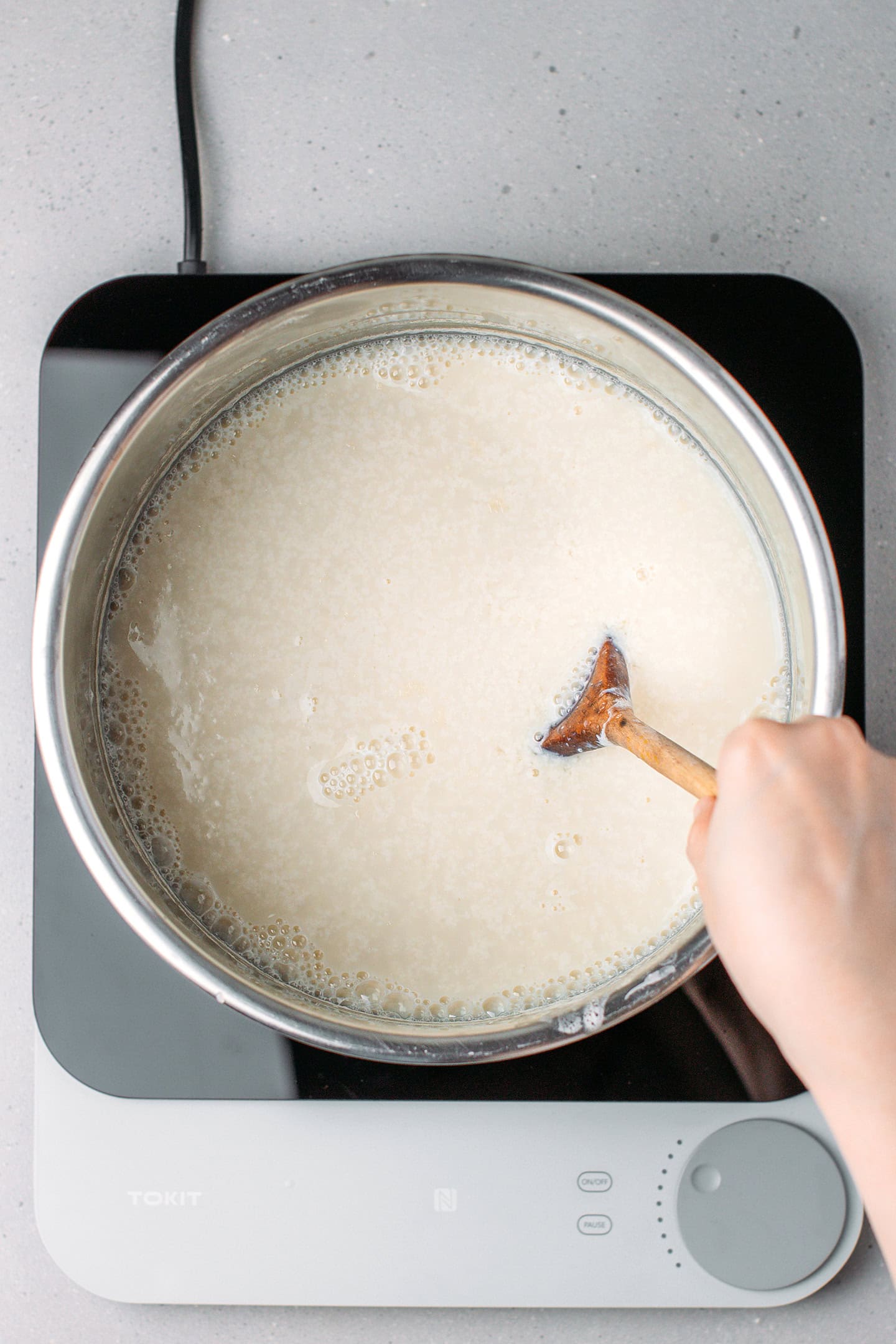 Stirring fava bean milk inside a pot.