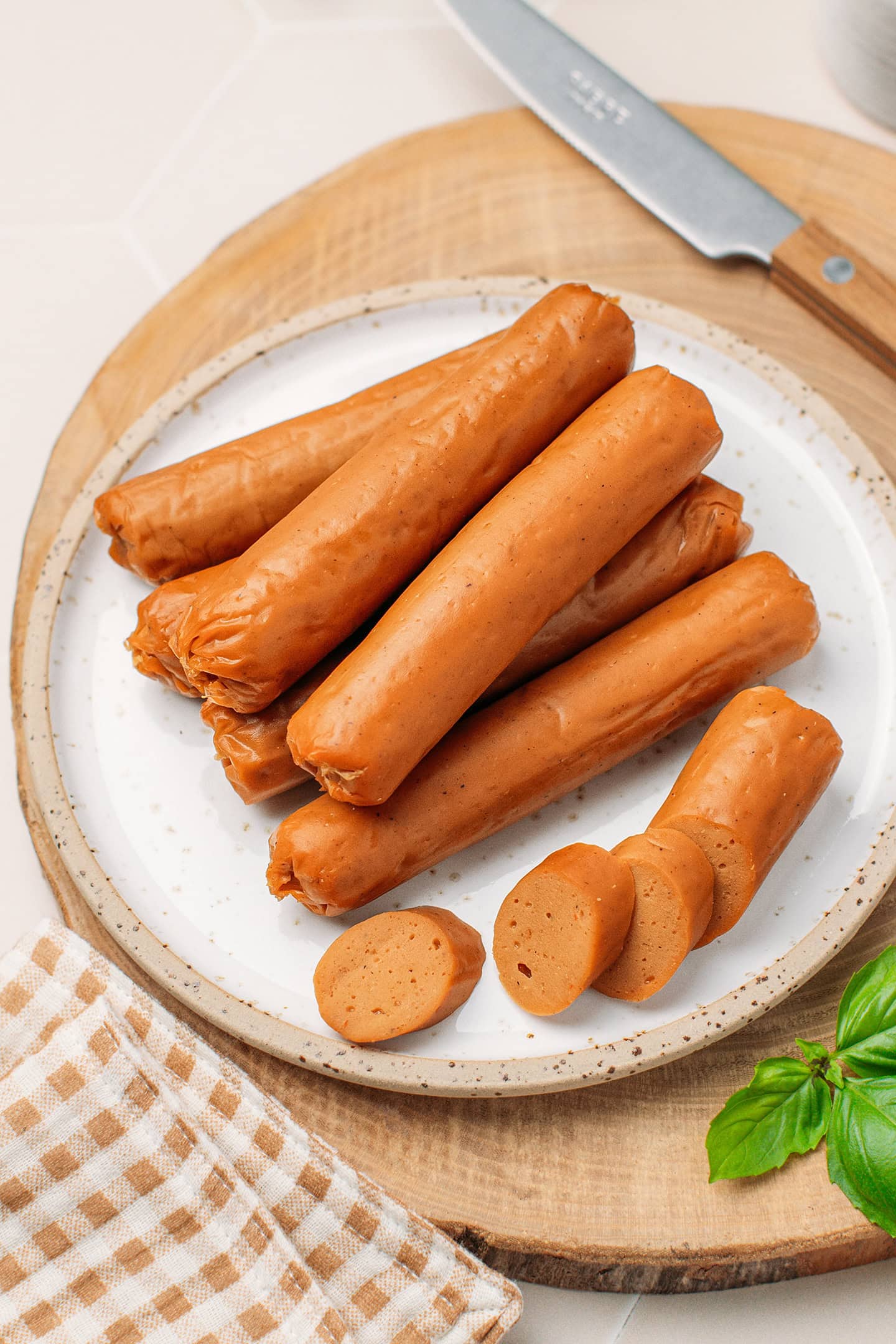 Vegan hot dog sausages on a small white plate.